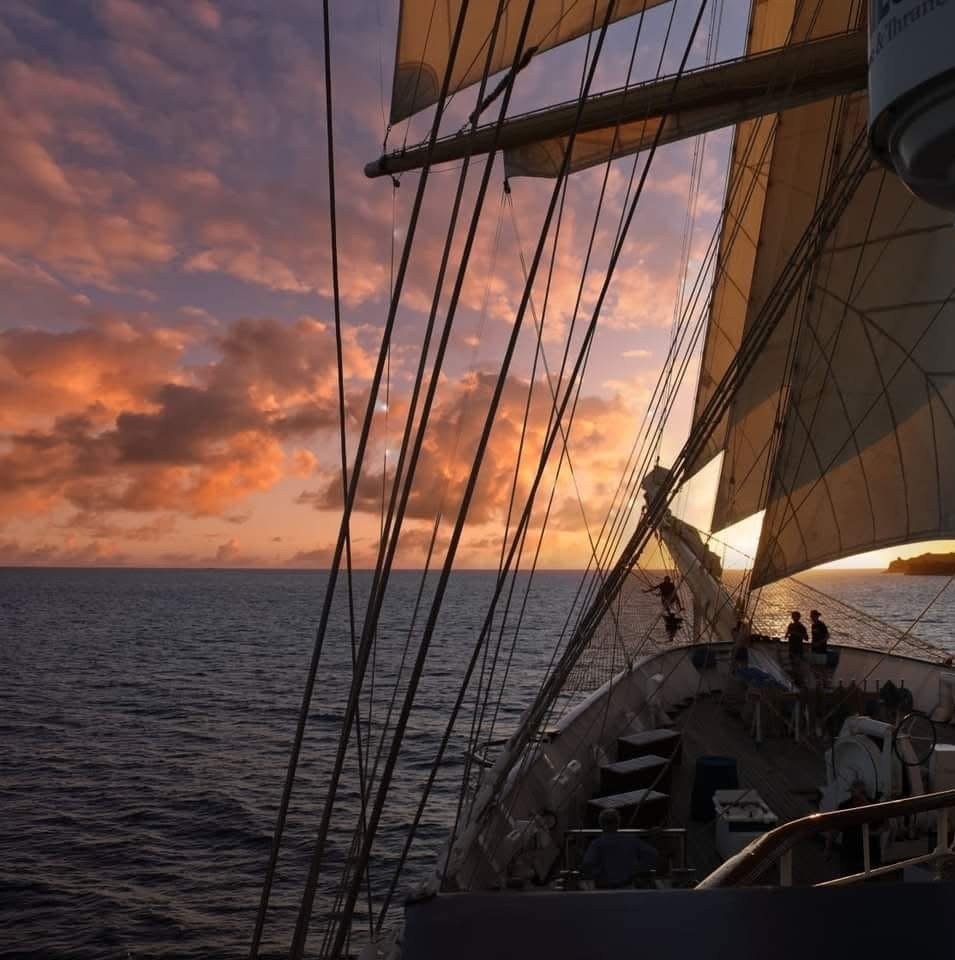 Sunset at sea beneath the sails and rigging of a tall ship