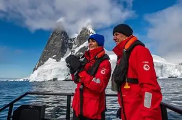 A person and person in red jackets standing on a boat

AI-generated content may be incorrect.