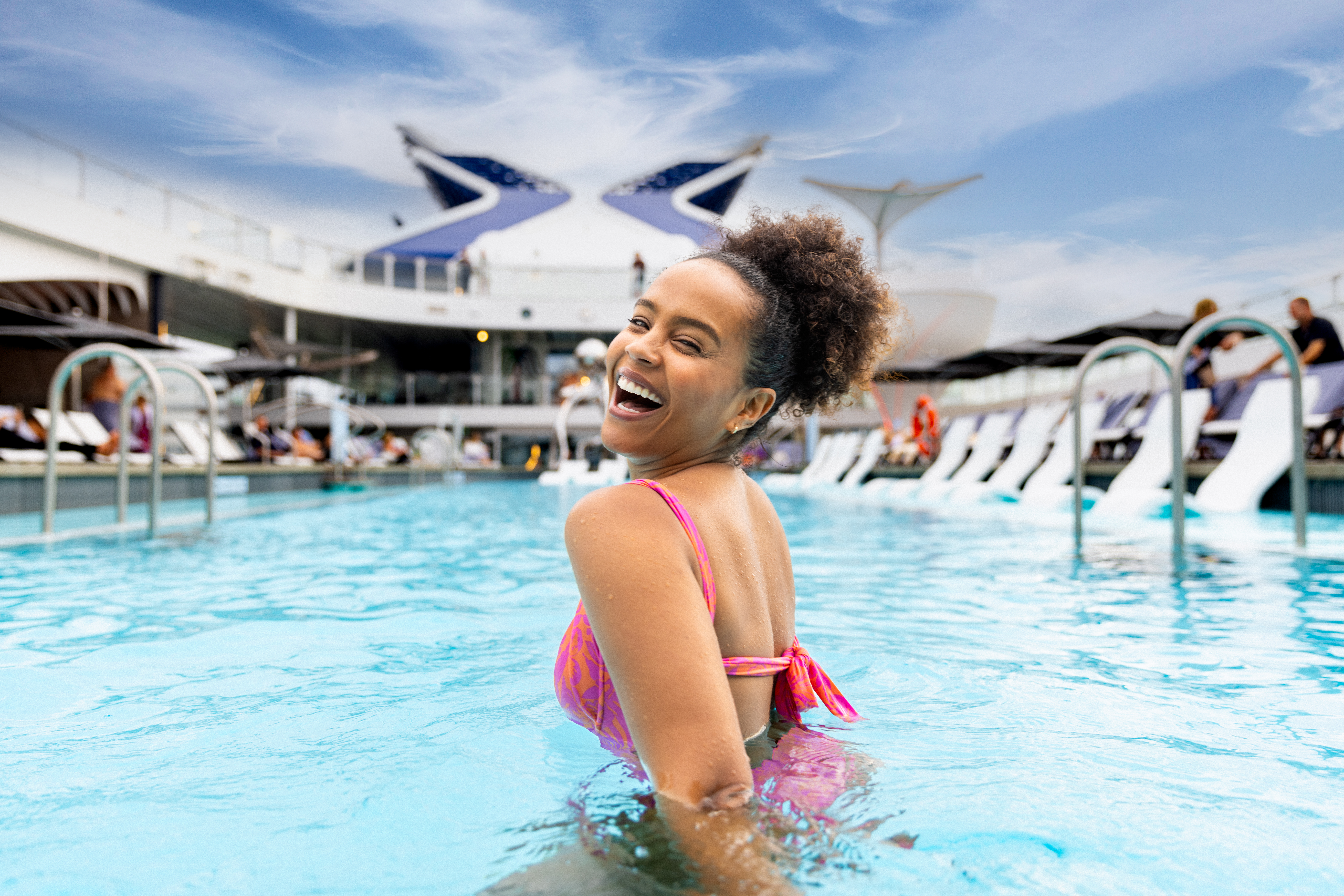 A woman laughs in the outdoor pool on Celebrity Cruises.