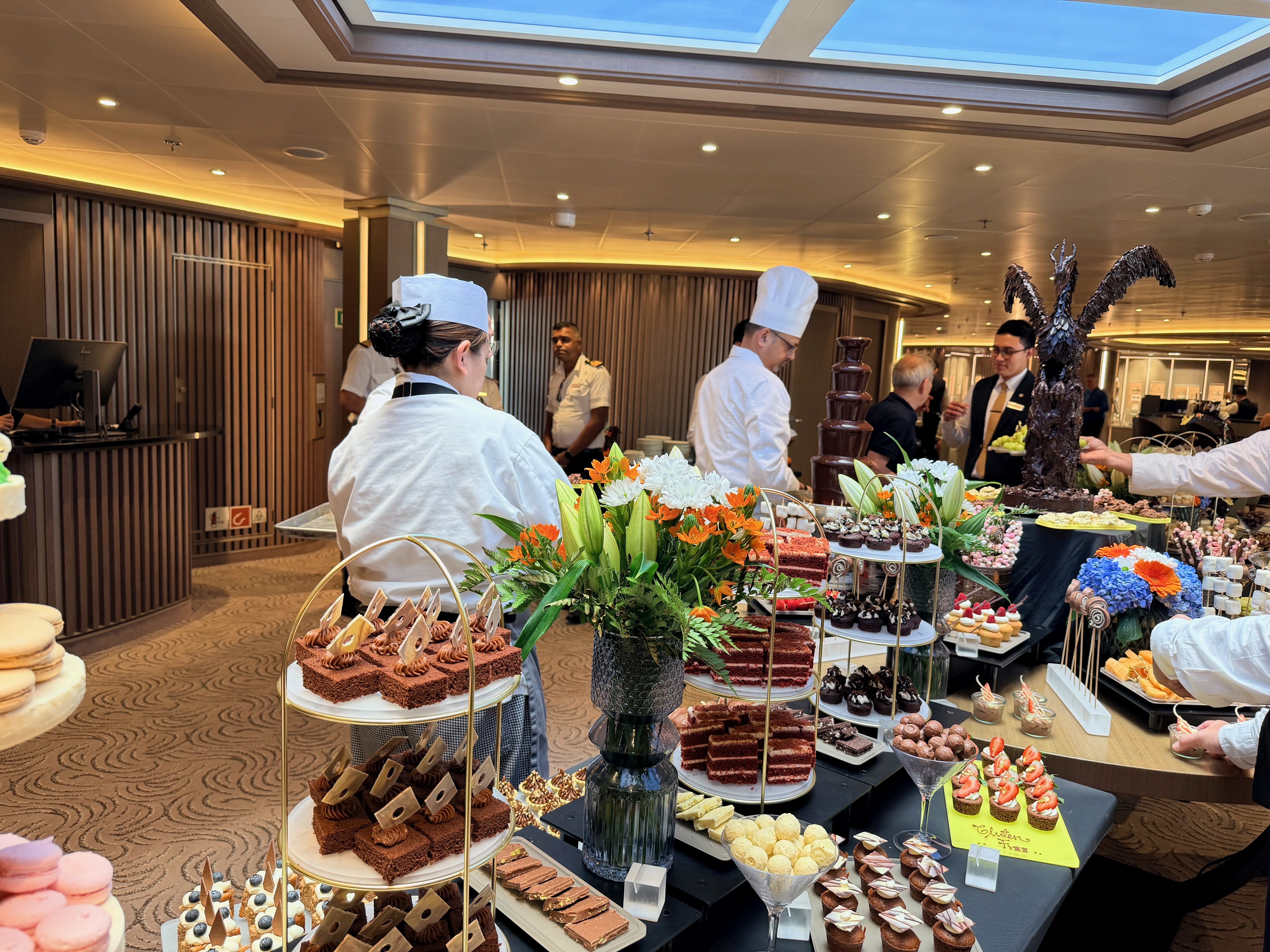 Cruise staff setting elaborate chocolate and sweets buffet with an exquisite chocolate showpiece of a dragon in the background