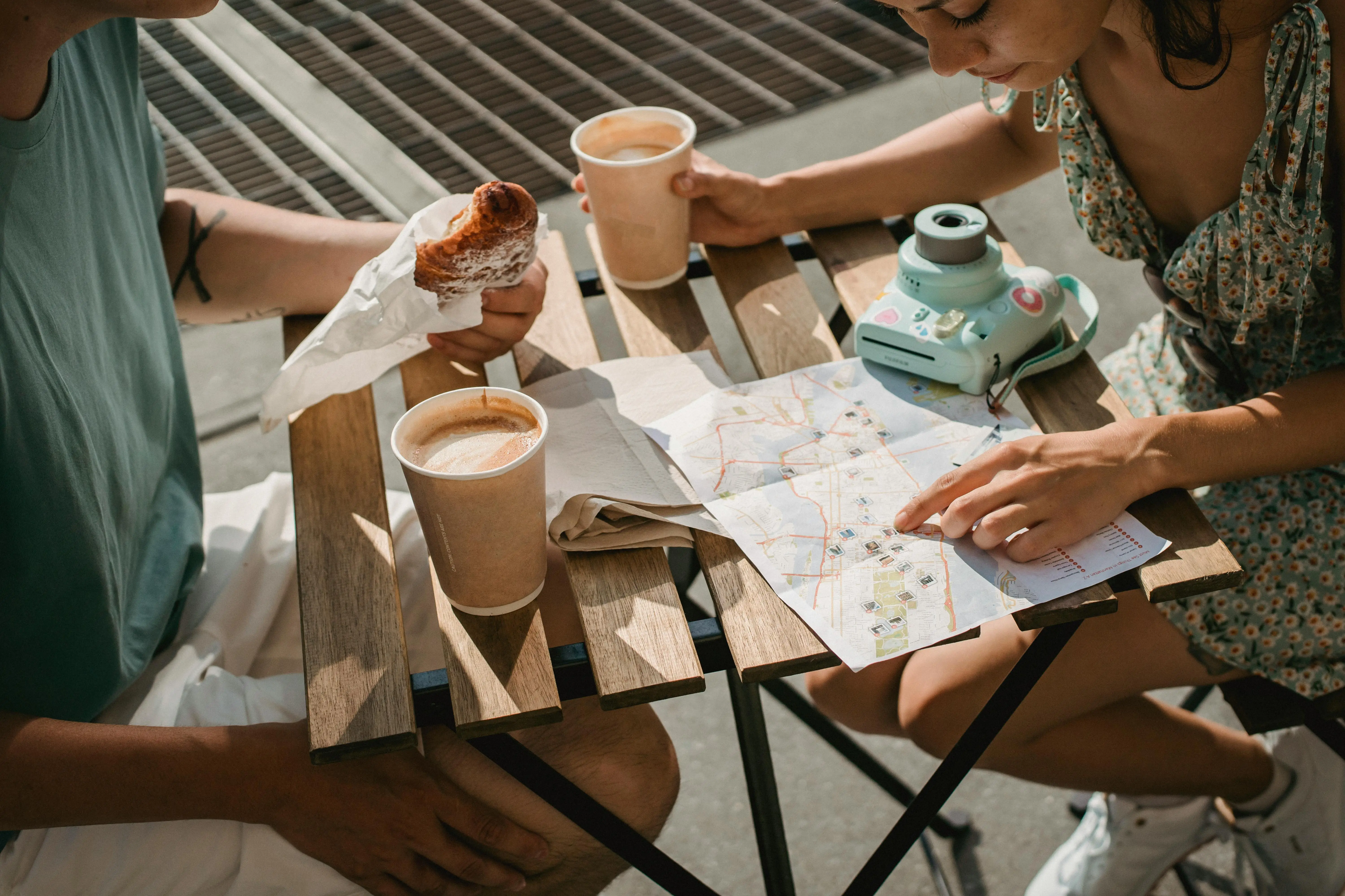 An image of two people drinking coffee an looking at a map.