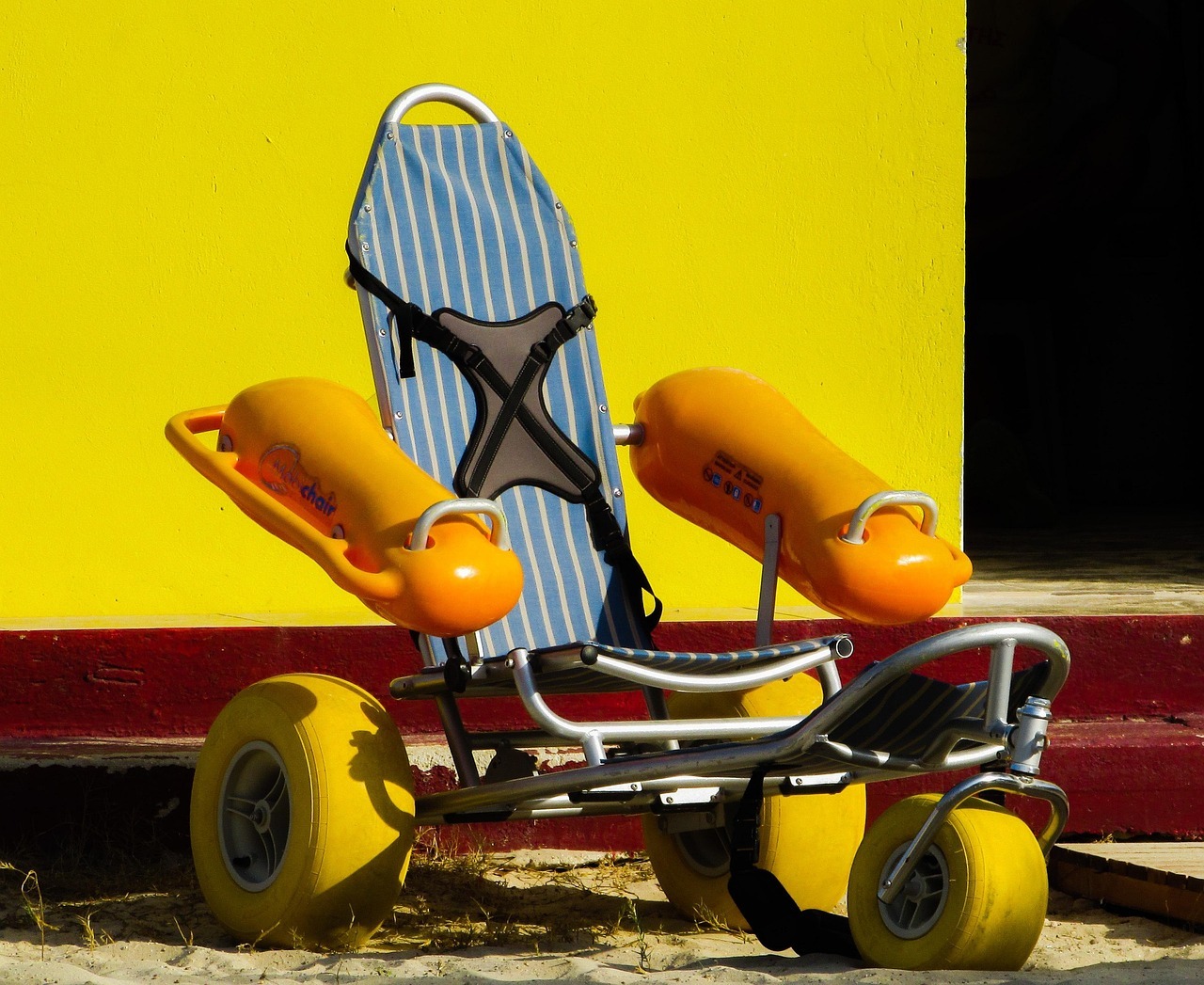 A beach wheelchair with large tires and floating armrests help those with mobility impairment enjoy the sand and water.