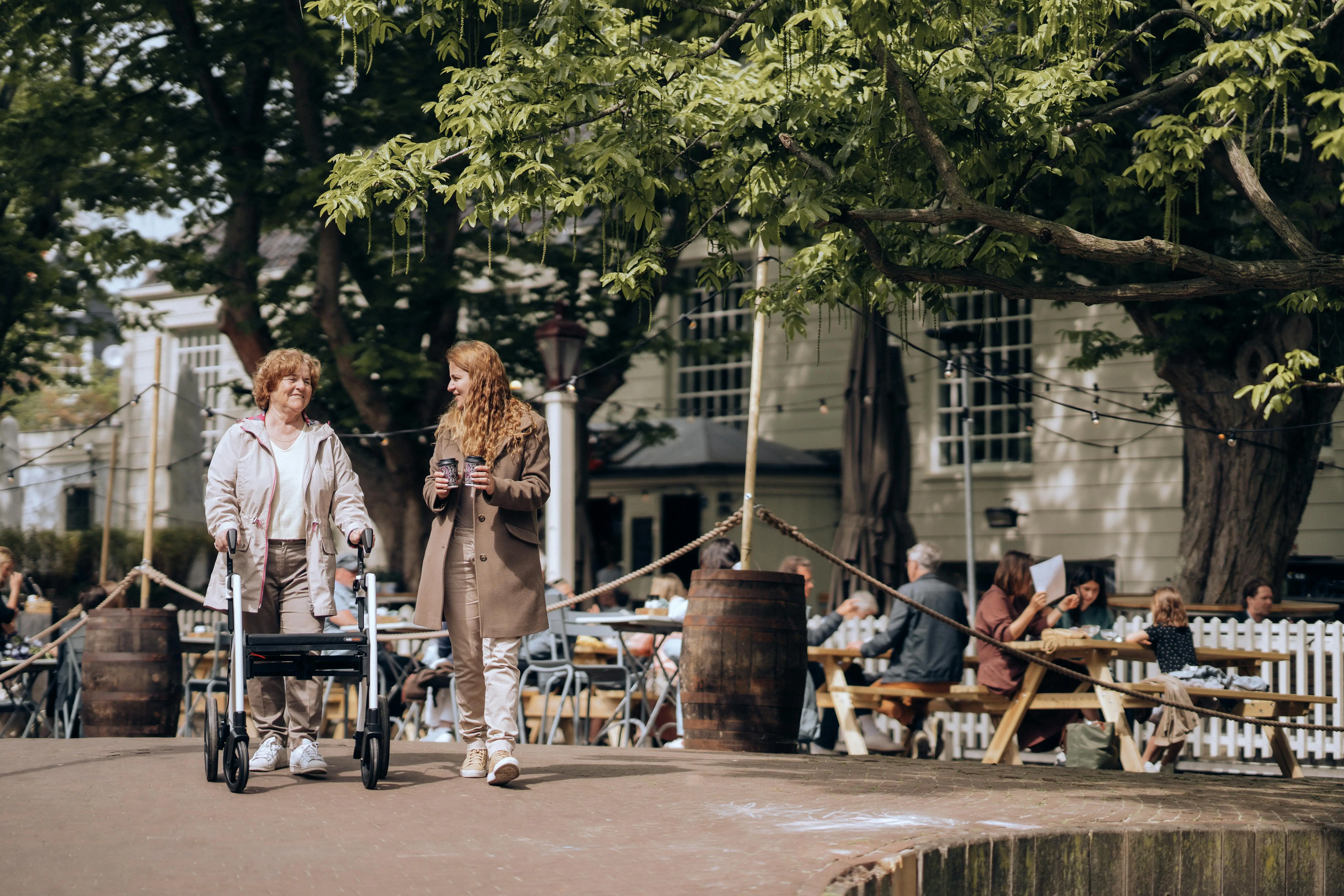 Two women walking, one using a walker/rollator.