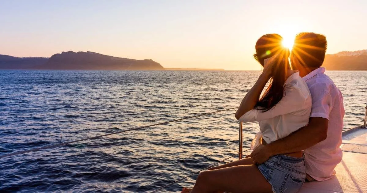 newlyweds on a boat looking out at sunset
